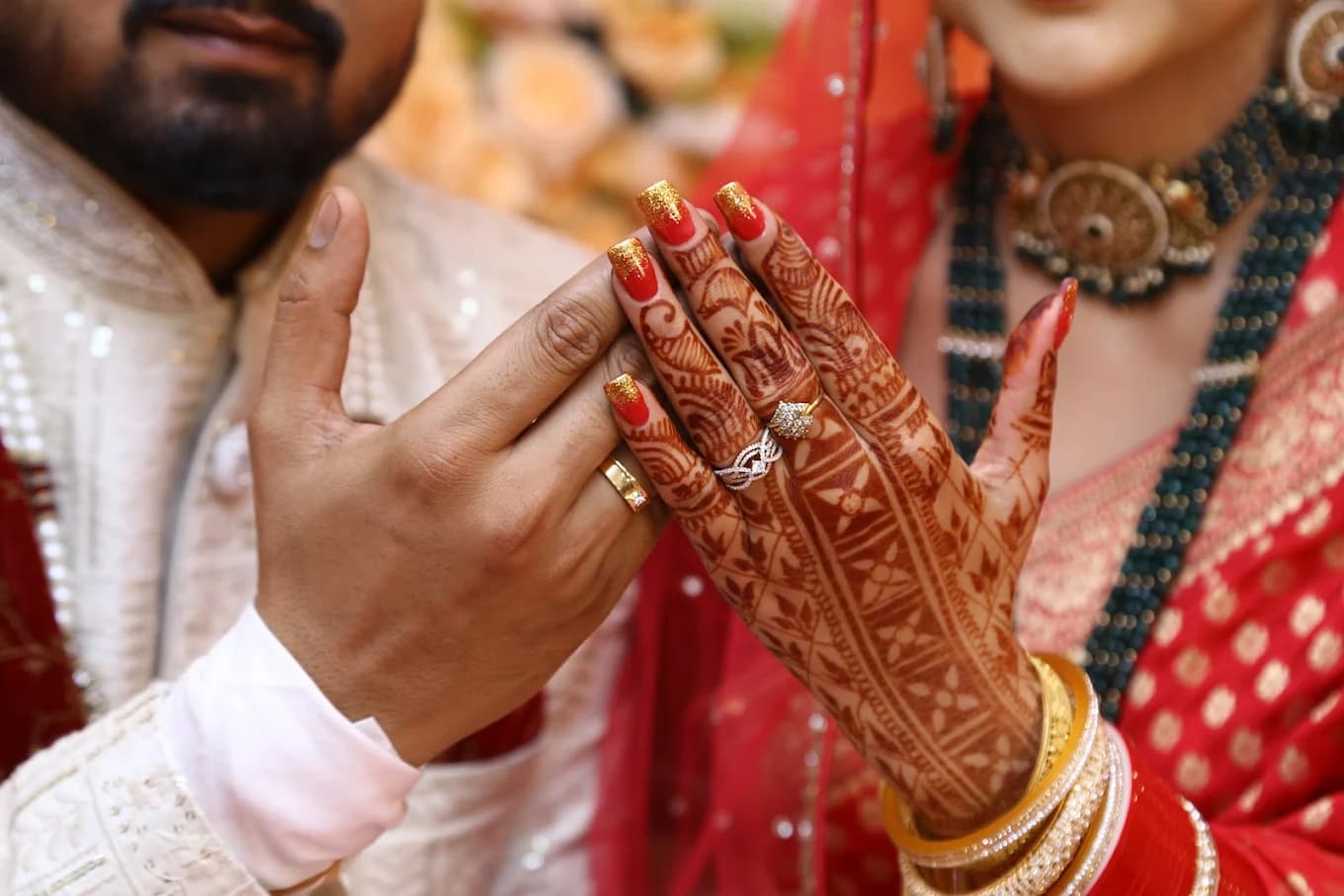 Couple hands with mehendi and wedding rings